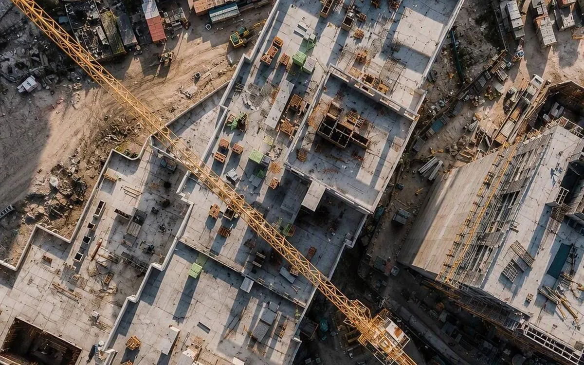 Senkrechtaufnahme einer Grossbaustelle mit Rohbaudecken, Kranausleger und Materiallagerplätzen